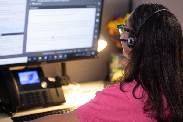 Woman who is visually impaired at her computer reviewing a website and has her headset on