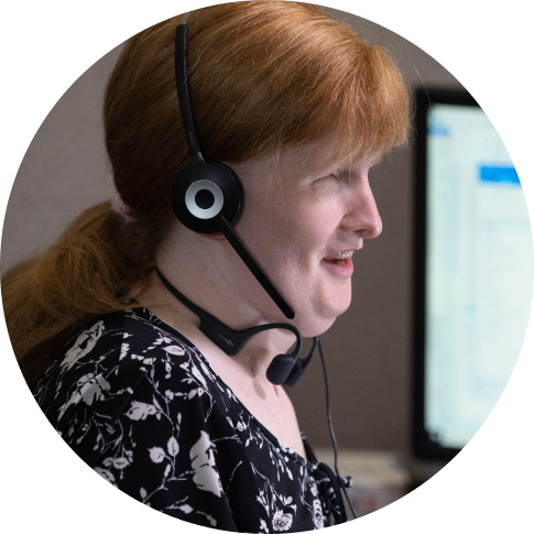 A contact center employee smiling as she's speaking with customers.