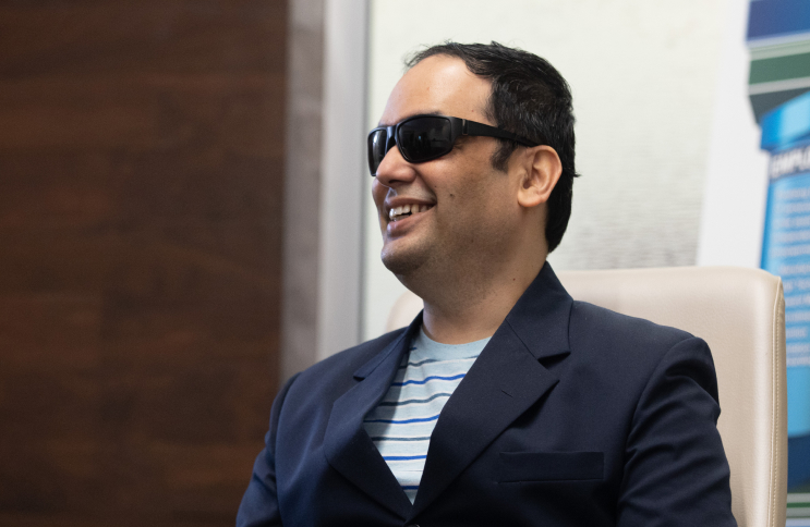 A blind man sitting in a chair and smiling.