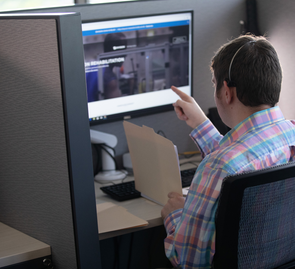 A call center service representative reviewing a file and pointing to a computer screen.