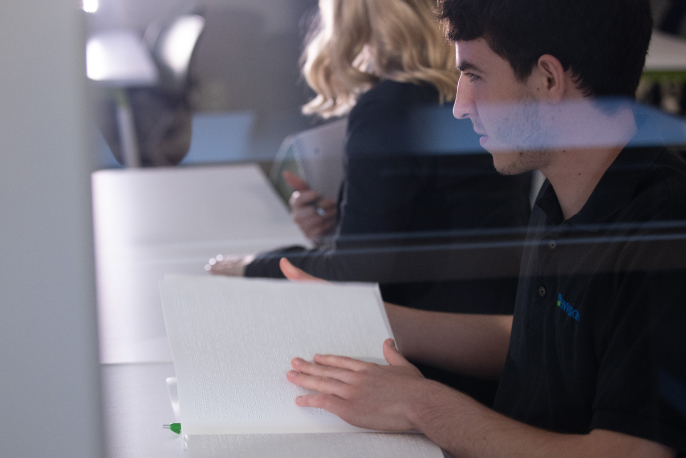 A blind employee reading notes in Braille.